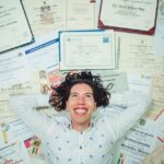 A happy man lies among certificates and diplomas, illustrating the eMudhra certificate authority security incident.