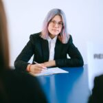 A young woman with dyed hair takes notes during a job interview, illustrating the process of switching industries mid-career.