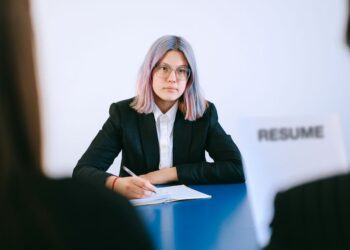 A young woman in a suit writing notes during a job interview, illustrating Chhattisgarh’s startup and NIPUN Mission initiatives.