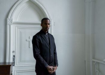 Young male minister holding a book before a church door, illustrating the PM Internship Scheme application process.