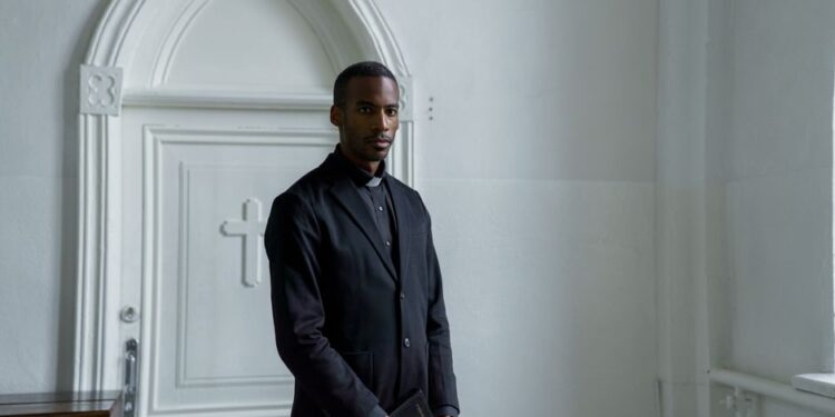 Young male minister holding a book before a church door, illustrating the PM Internship Scheme application process.