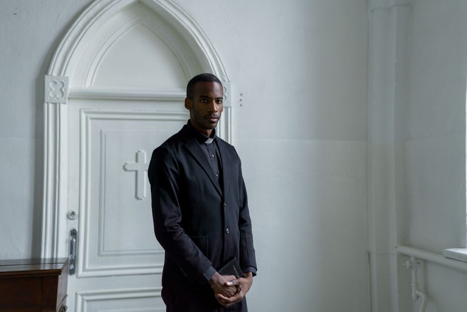 Young male minister holding a book before a church door, illustrating the PM Internship Scheme application process.