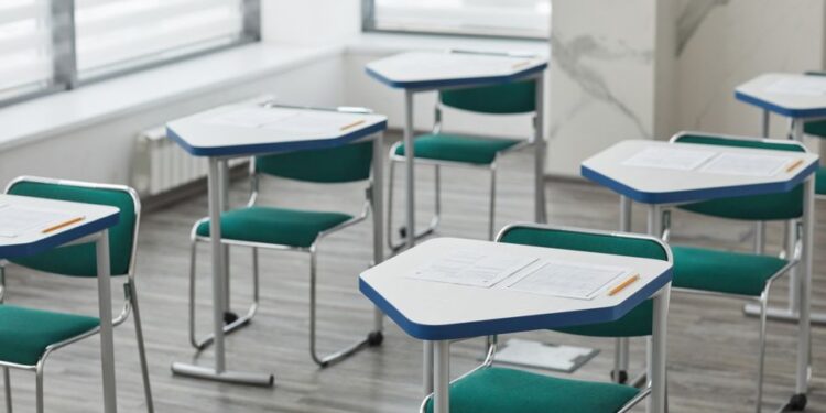 Empty classroom with desks, exam papers and pencils arranged, illustrating the Telangana SSC March 2027 exam fee schedule.