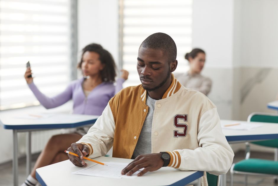 Stock photo of A student concentrating on an exam in a classroom setting, holding a pencil, used to illustrate this story on Assam Sets Exams for over Five Thousand Seven Hundred Posts.