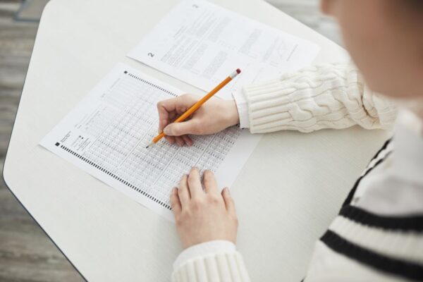 A student filling out a multiple-choice exam in a quiet classroom, illustrating the OUSSSC application process for uniformed services posts.