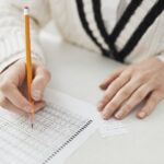 Stock photo of A student writing answers on a multiple-choice exam sheet at a desk, used to illustrate this story on ICAI Has Not Confirmed CA Foundation September Result Date.