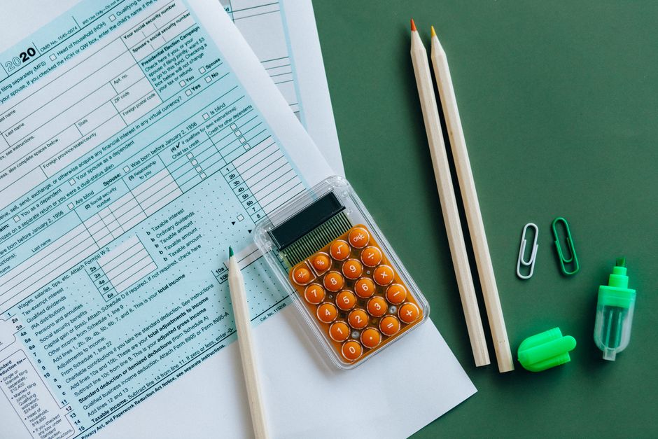 Stock photo of flat lay of tax forms, calculator, pencils, and clips on green surface, used to illustrate this story on Savings Tax Rates Rise to 24%, 44% and 49% from 6 April.