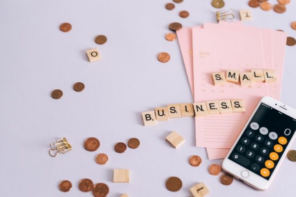 Stock photo of flat lay image of small business finance concept with coins, calendar, and smartphone calculator, used to illustrate this story on India’s Fast-Track GST Registration: Who Qualifies and What to Check.