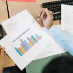 Stock photo of A business analyst reviews a colorful bar chart and documents at a desk, indicating, used to illustrate this story on How Walmart Finds Lookalike Customers for E-Commerce Campaigns.