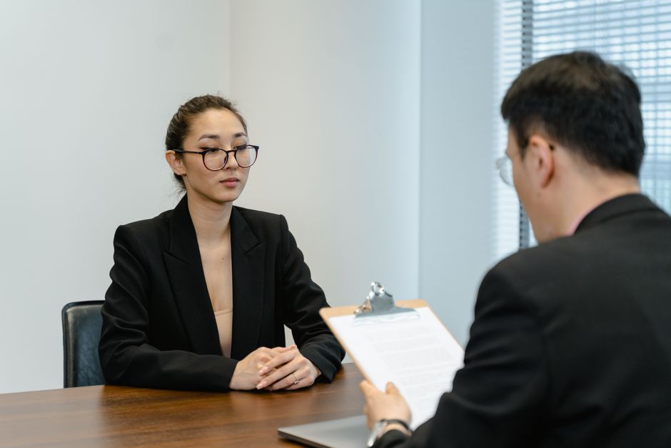 Two professionals sit across a desk in a modern office, discussing documents, illustrating tech layoffs.