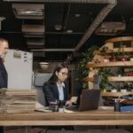 A business team collaborating in an office with plants and documents, illustrating first ninety days at a new job.