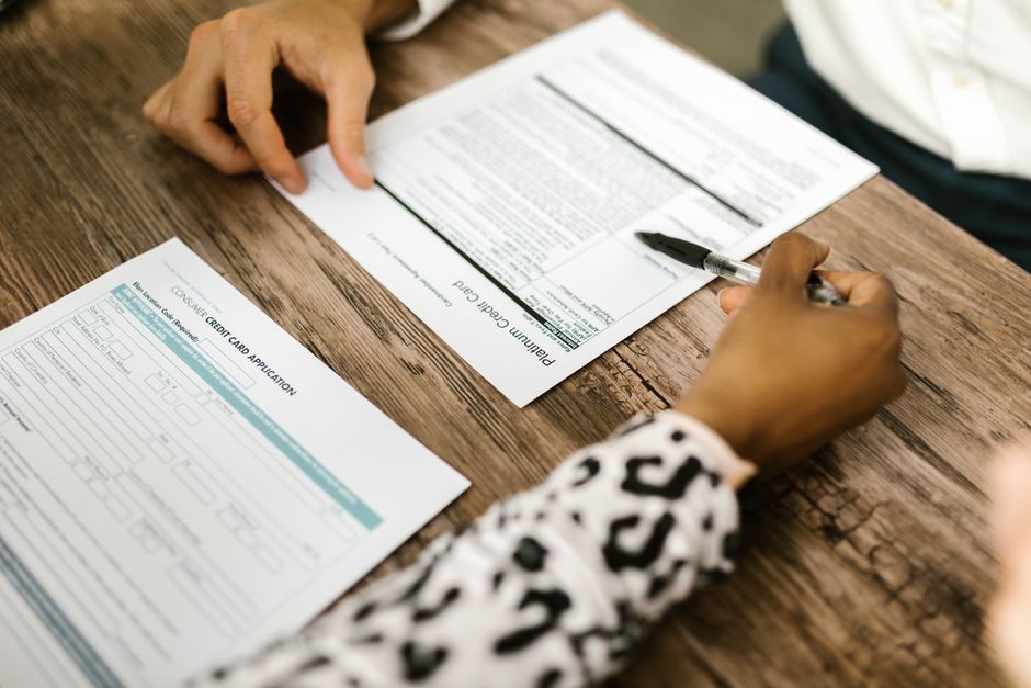 Stock photo of Close-up of two people reviewing and filling out a credit card application on a, used to illustrate this story on UPPSC Approves 501 RO, ARO Vacancies for 2026 Recruitment.