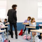 A teacher watches over students doing classroom activities, illustrating how US teachers move more work into class as AI spreads.