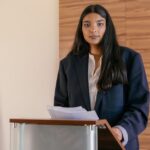 A woman in a suit presenting at a podium, illustrating the UK Chancellor’s budget test.