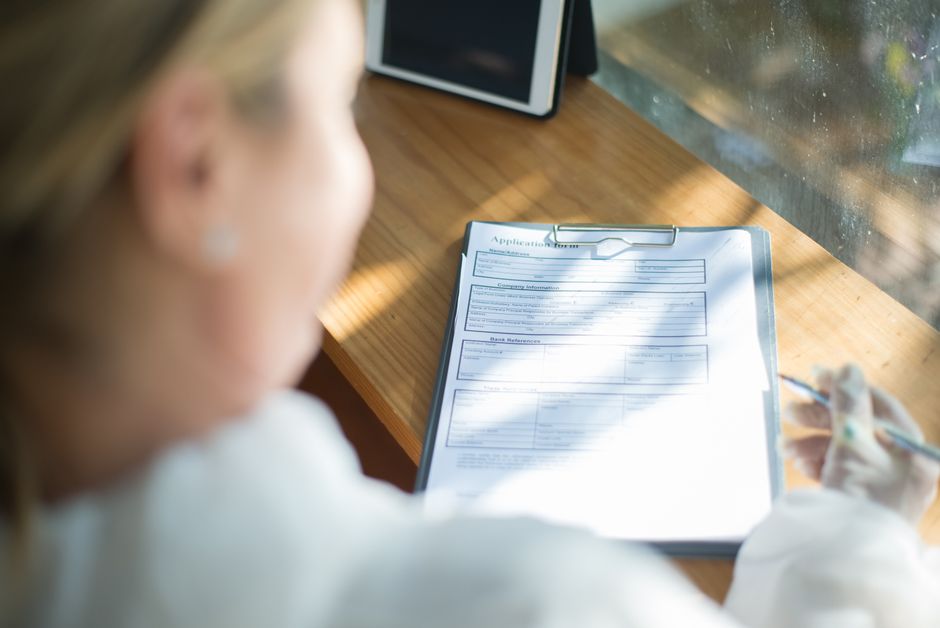 Stock photo of A woman fills out an application form with a pen at a sunlit wooden, used to illustrate this story on Andhra Pradesh Extends Government Job Age Limit to 44 Through 2027.