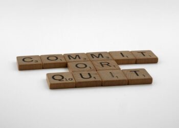 Scrabble tiles spelling “Commit Or Quit” on a white surface, illustrating decision‑making in a new job’s first 90 days.