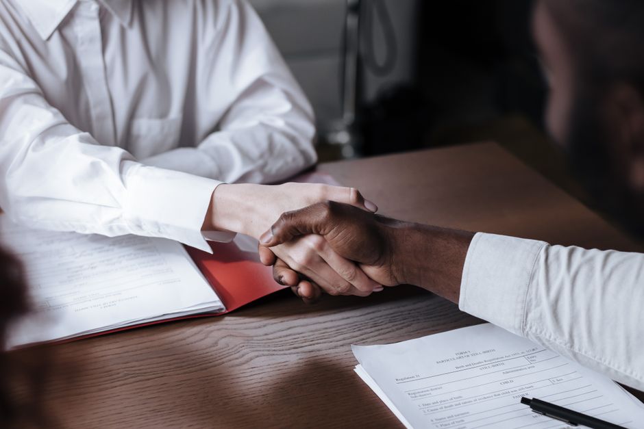 A diverse business handshake over documents, illustrating the Salesforce-Rune Technologies acquisition agreement.