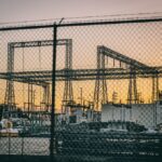 A substation at sunset with a fence in the foreground, illustrating halted power licence proceedings in Haryana.