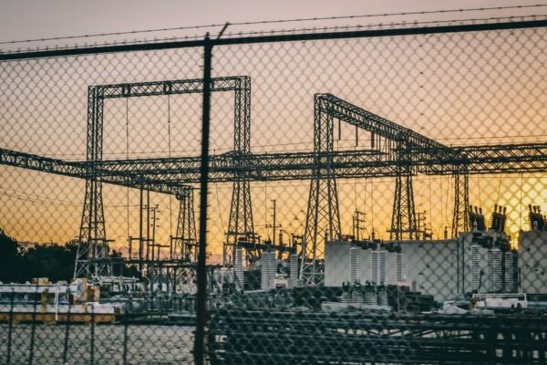 A substation at sunset with a fence in the foreground, illustrating halted power licence proceedings in Haryana.