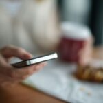 A person holding a gray phone in selective focus, illustrating Google’s AI Mode ads expansion.