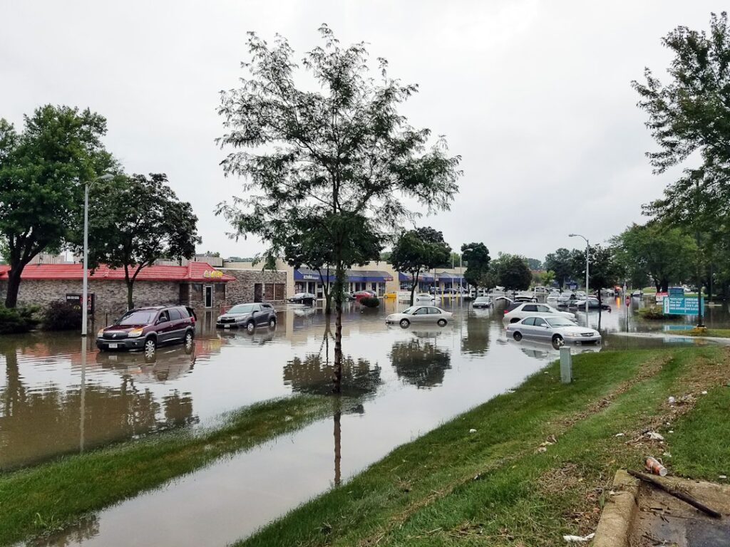 Cars drive through a flooded street, illustrating travel disruption from Storm Boelo in the UK.