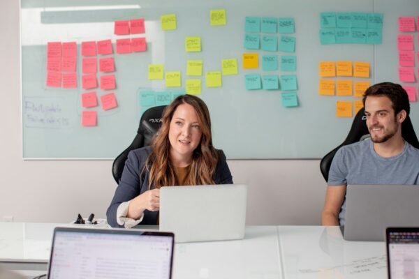 Stock photo of woman in black shirt sitting on chair in front of laptop computer, used to illustrate this story on How to Compare Remote and Hybrid Work Terms.