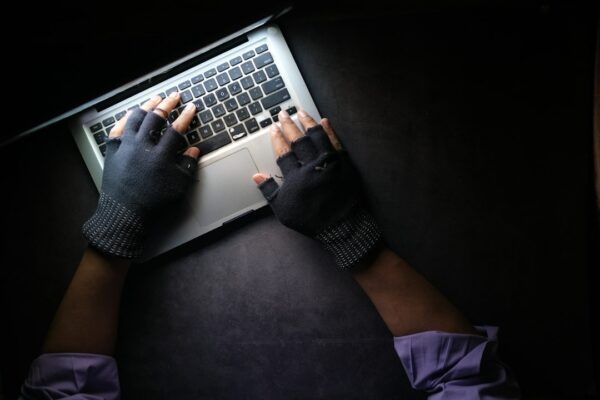 A person wearing fingerless gloves typing on a laptop on a dark surface, illustrating the Binance crypto heist.