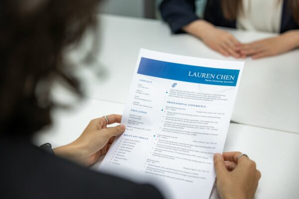 A woman reading a resume at a table, illustrating ethical preparation for a job interview.