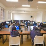 Stock photo of students in hijabs working at computers in a bright school computer lab, used to illustrate this story on Education Ranks as the Most Cyber-Attacked Sector.