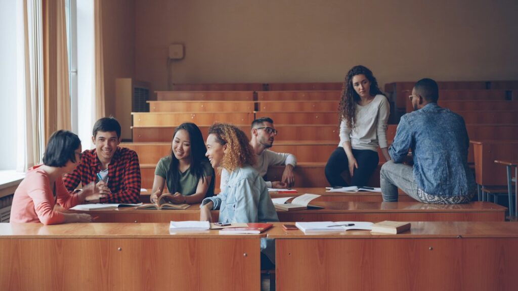 Stock photo of students talking in a lecture hall classroom, used to illustrate this story on How to Choose a Degree by Fit, Course Content and Cost.