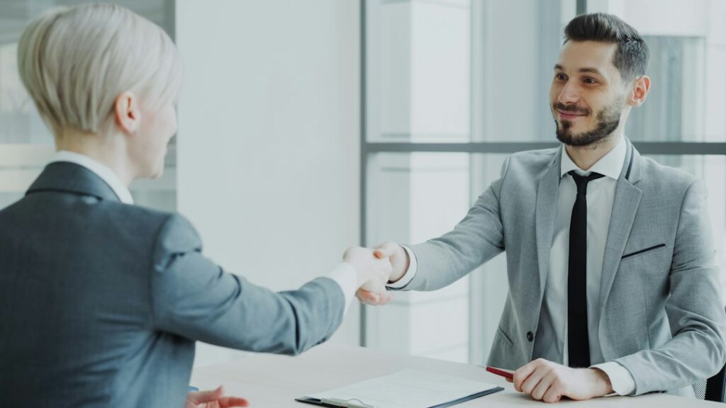 Two professionals shaking hands across a table, illustrating collaboration in a changing job market.