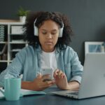 A young girl wearing headphones uses a phone at a desk, illustrating social media use in a teen addiction case.
