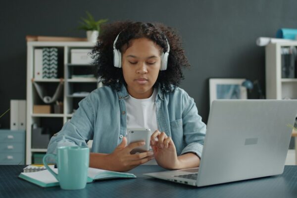 A young girl wearing headphones uses a phone at a desk, illustrating social media use in a teen addiction case.