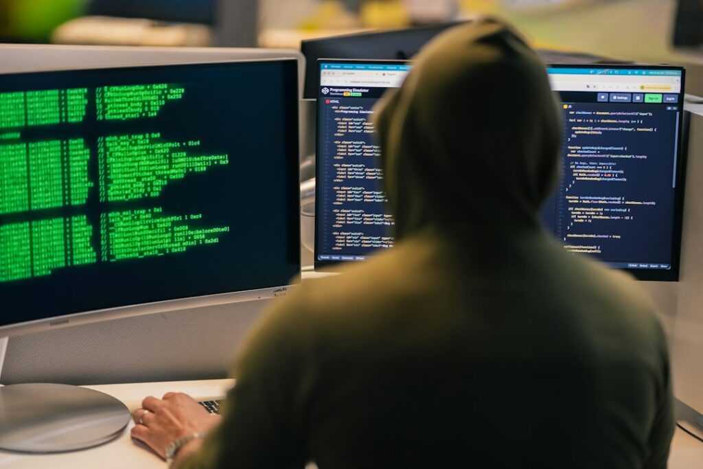 A hacker in a hoodie working on multiple computer screens, illustrating the Binance crypto heist.
